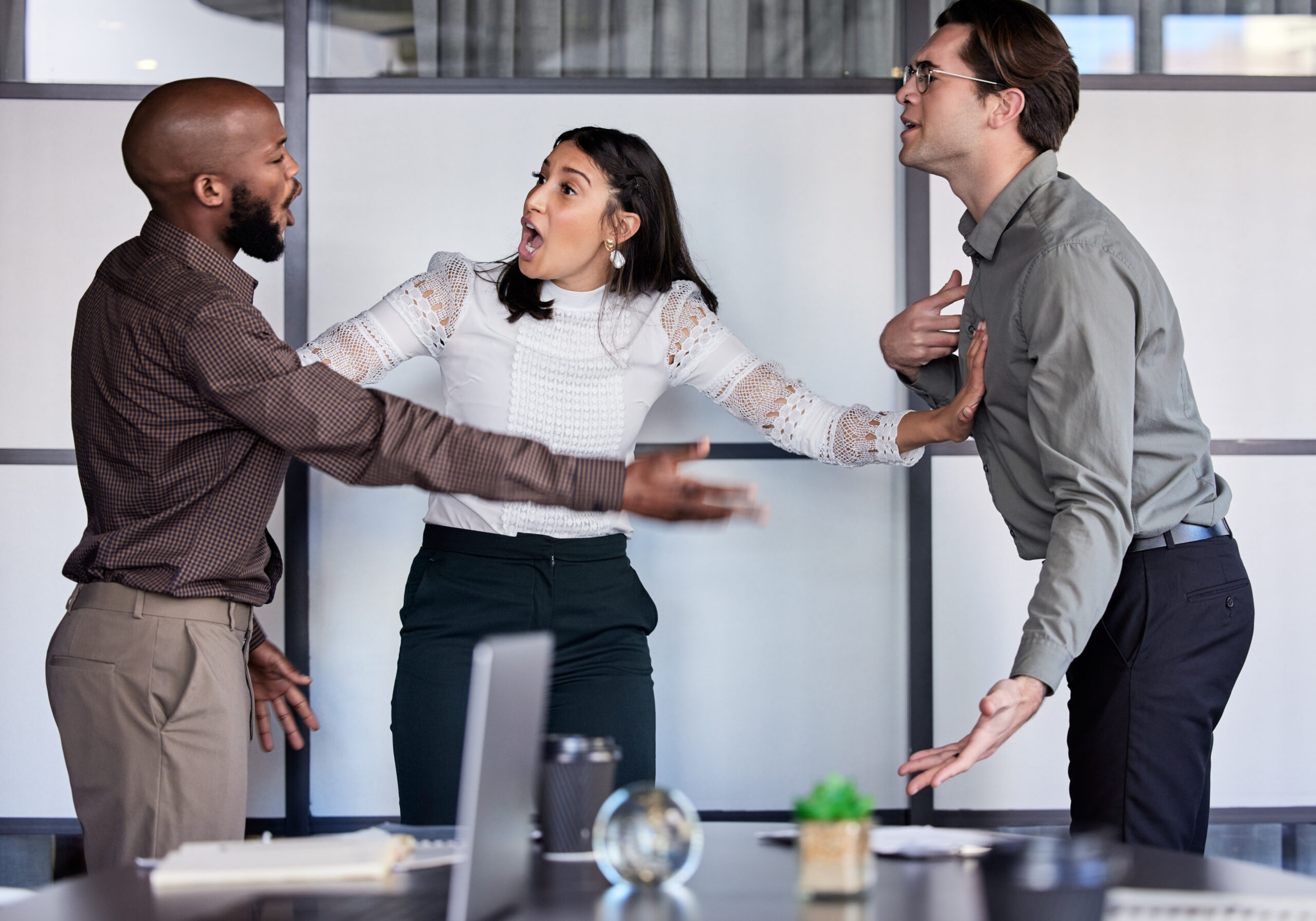 Trois colleagues en conflit au bureau, gesticulant et se disputant, prêt-à-propos prêt à s’affronter.