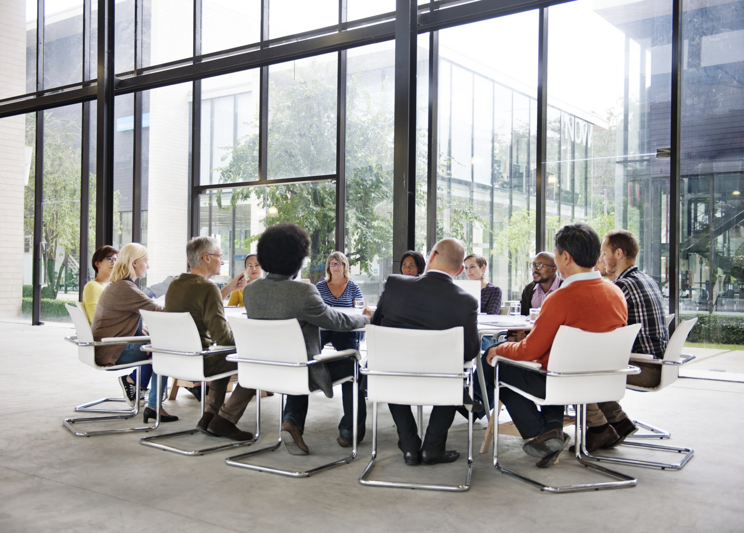 Groupe de professionnels autour d’une table en réunion, discutant en cadre lumineux, illustration de négociation et gestion de conflits en entreprise